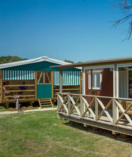 Holzbungalow mit Veranda auf einem sonnigen Campingplatz.