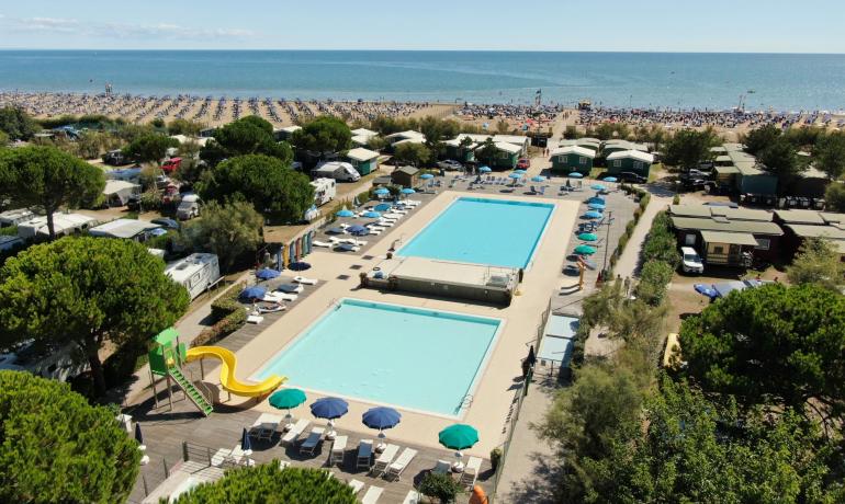 Luftaufnahme eines Campingplatzes mit Pools in Strandnähe.
