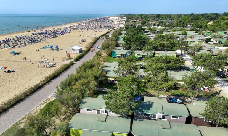 Crowded beach with umbrellas and mobile homes near the sea.
