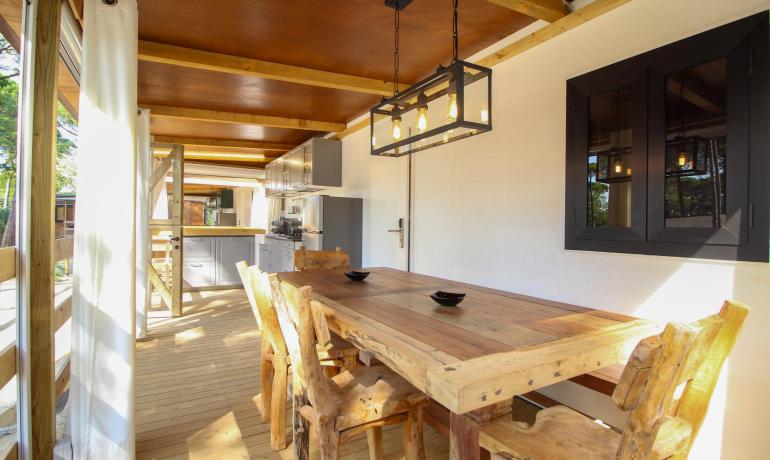 Rustic dining room with wooden table and modern chandelier.
