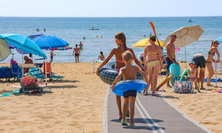 Families on the beach with children and colorful umbrellas.