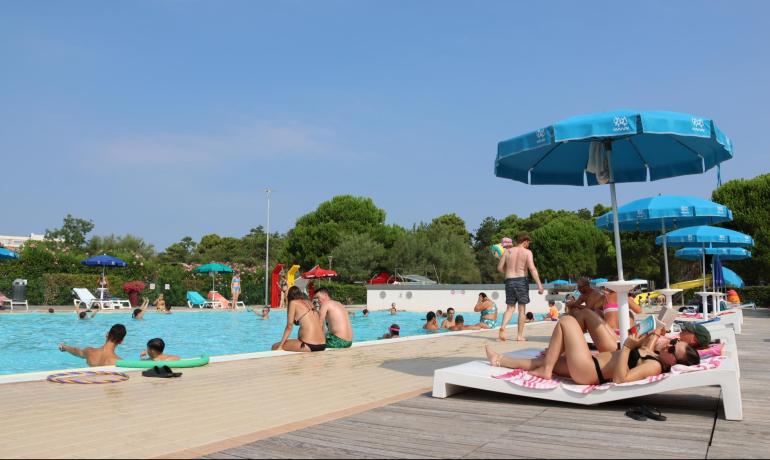 Freibad mit Schwimmern und blauen Sonnenschirmen.