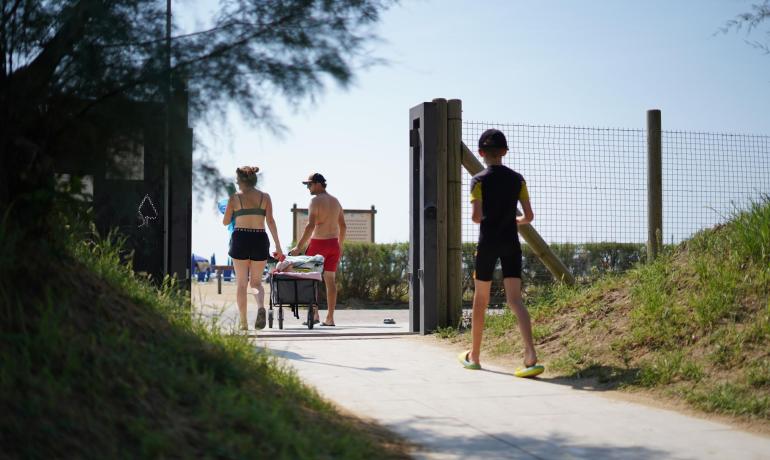 Menschen gehen auf einem sonnigen Weg zum Strand.